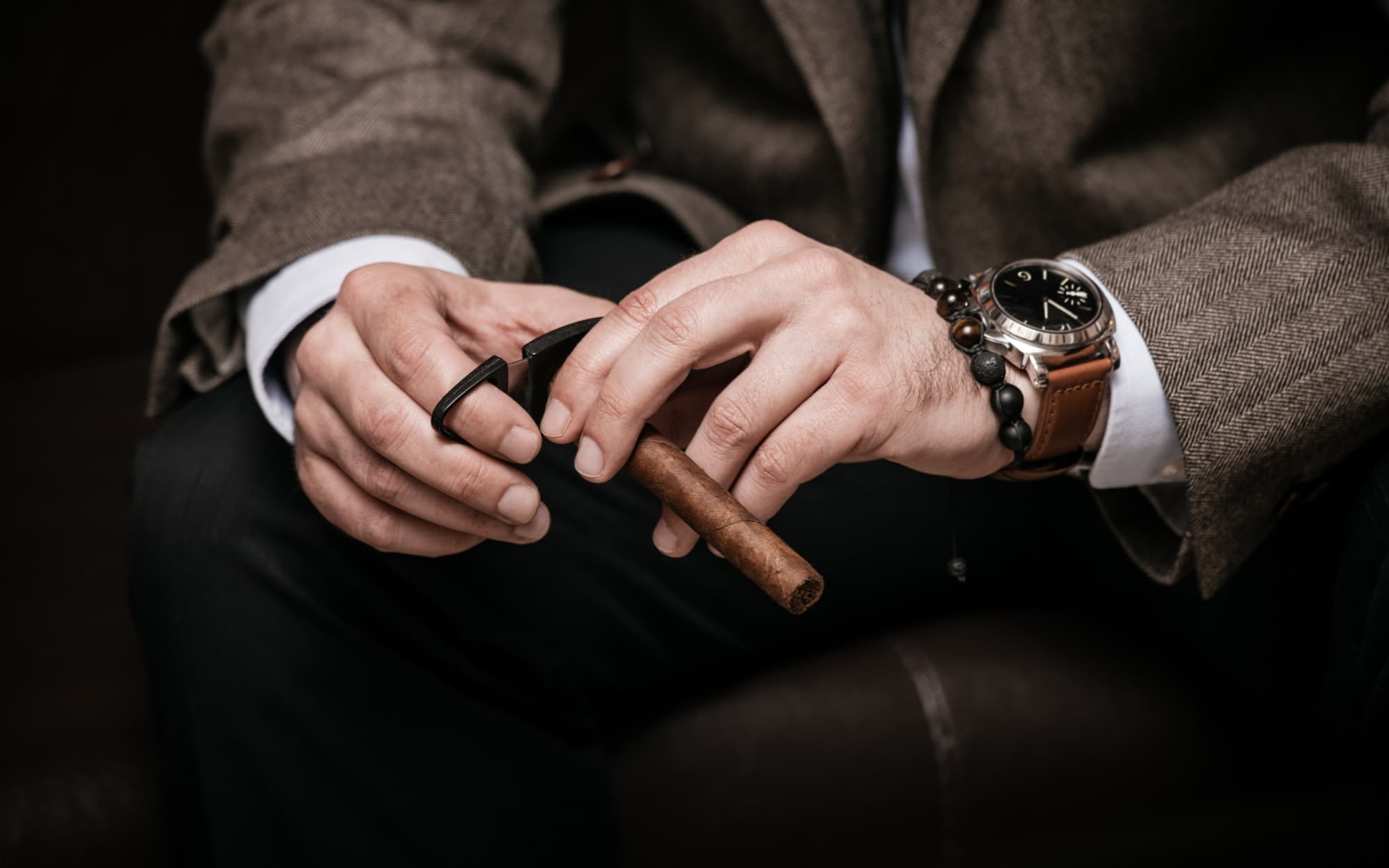 Man holds cigar and cigar cutter in hands.